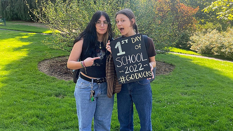 Two students pose with a sign for the first day of classes