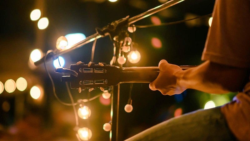 close up of person playing a guitar at a concert